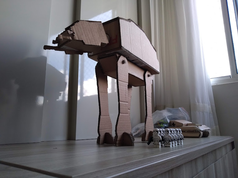 A cardboard AT-AT with a platoon of Lego Stormtroopers marching at its side